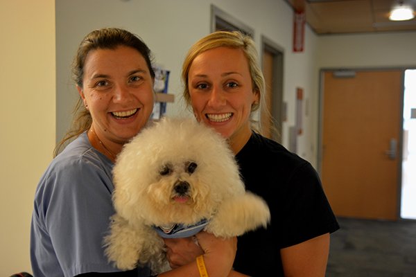 Two UNC Staff members smiling while holding Tar Heel Paws Team Dog Pippin